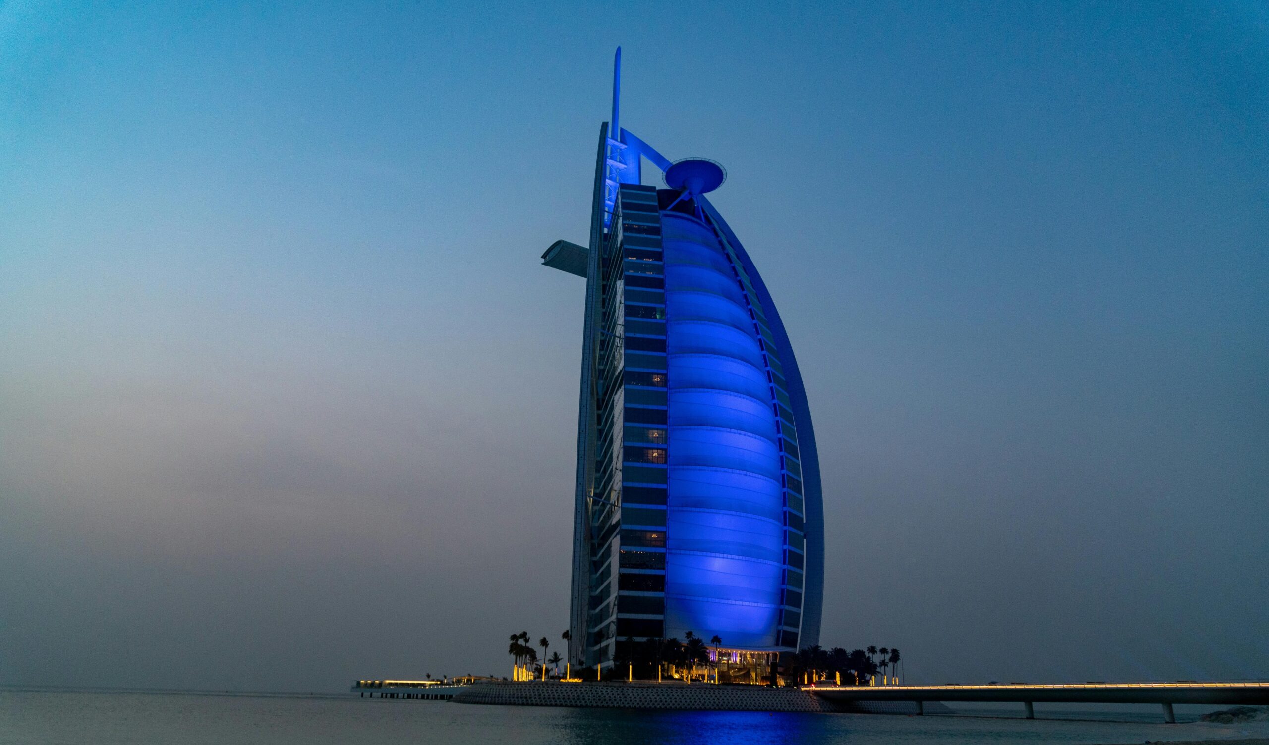 Stunning view of Burj Al Arab lit up in blue at twilight in Dubai, UAE.